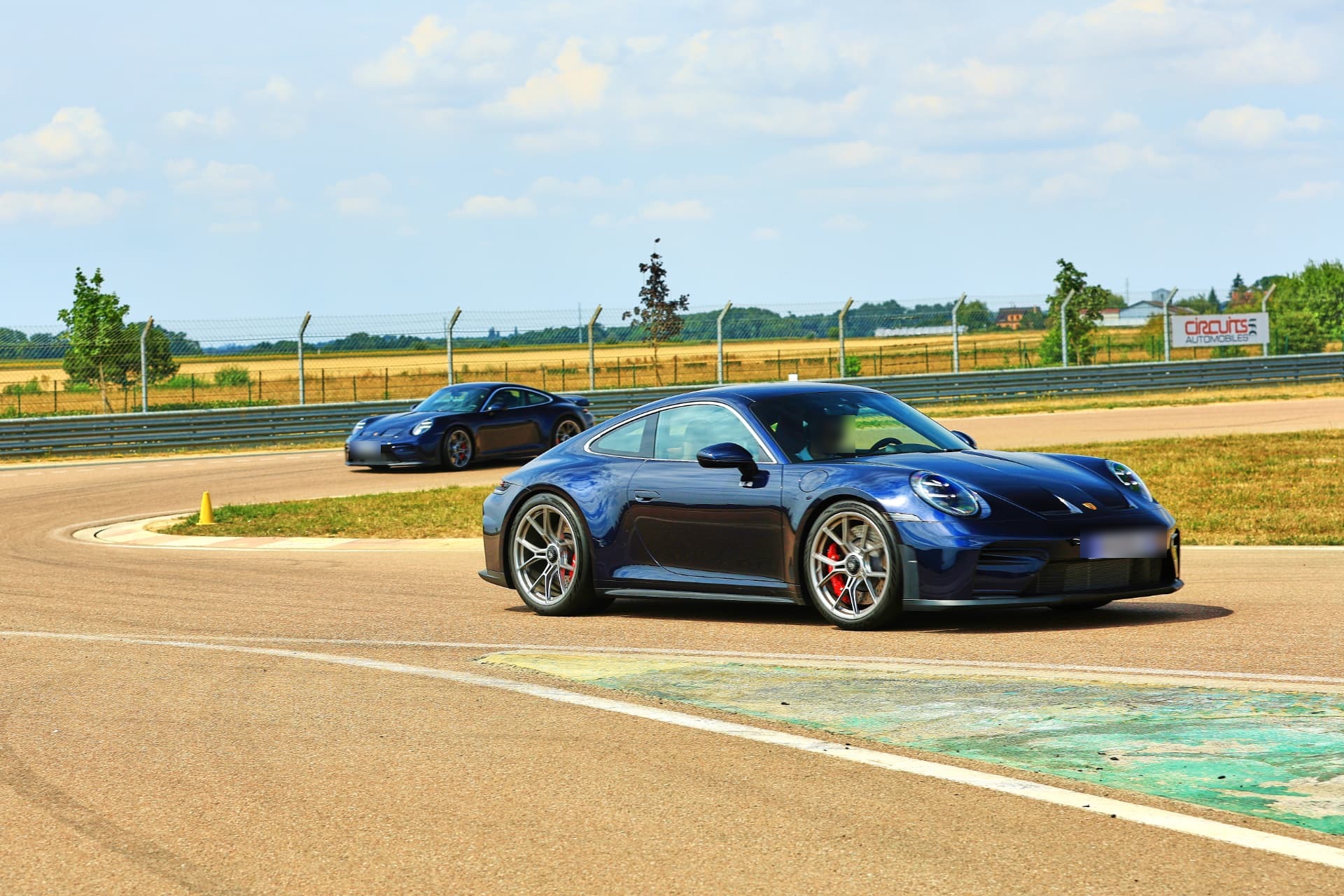 Deux Porsche 911 GT3 Touring en enfilade dans un virage de circuit